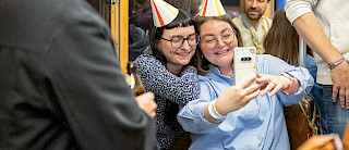 Teammitglieder bei Firmenfeier mit Partyhüten und Selfie
