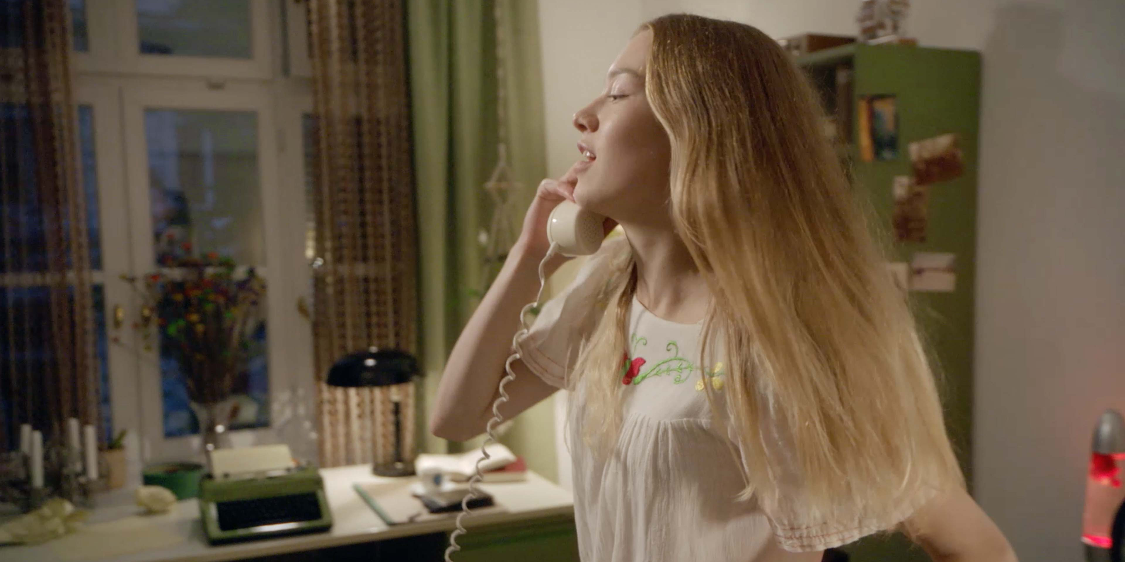 Eine junge Frau die enthusiastisch des Hörer eines Kabeltelefons abhebt